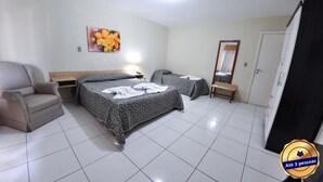 Una camera d'albergo con due letti, una sedia, una panca, uno specchio e un quadro appeso al muro.