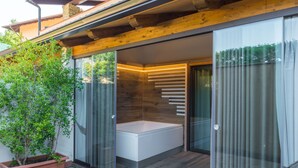 Un baño moderno con cabina de ducha de vidrio, una bañera blanca y una planta en maceta.