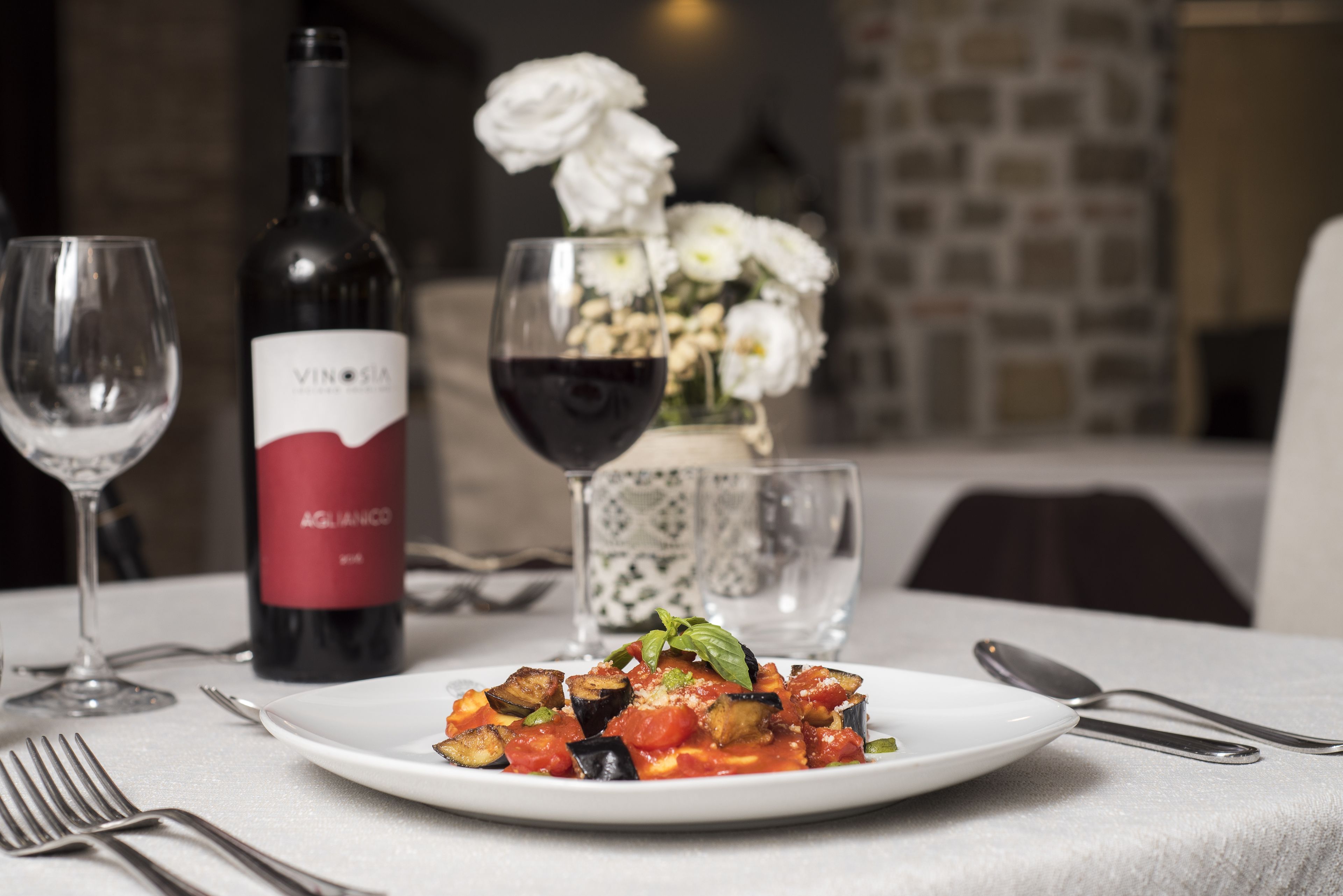 A dining table with a plate of food, a wine bottle, and glasses.