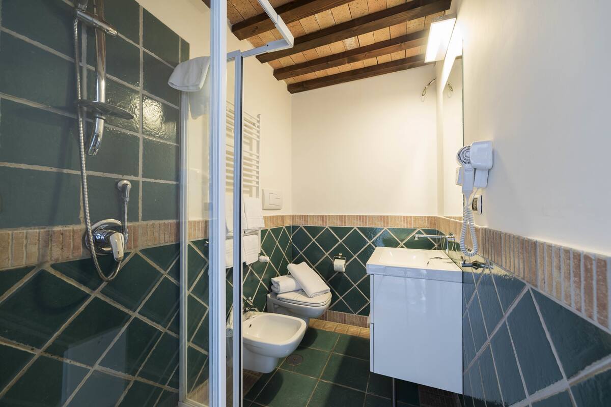 A bathroom with a shower, toilet, bidet, and a sink.