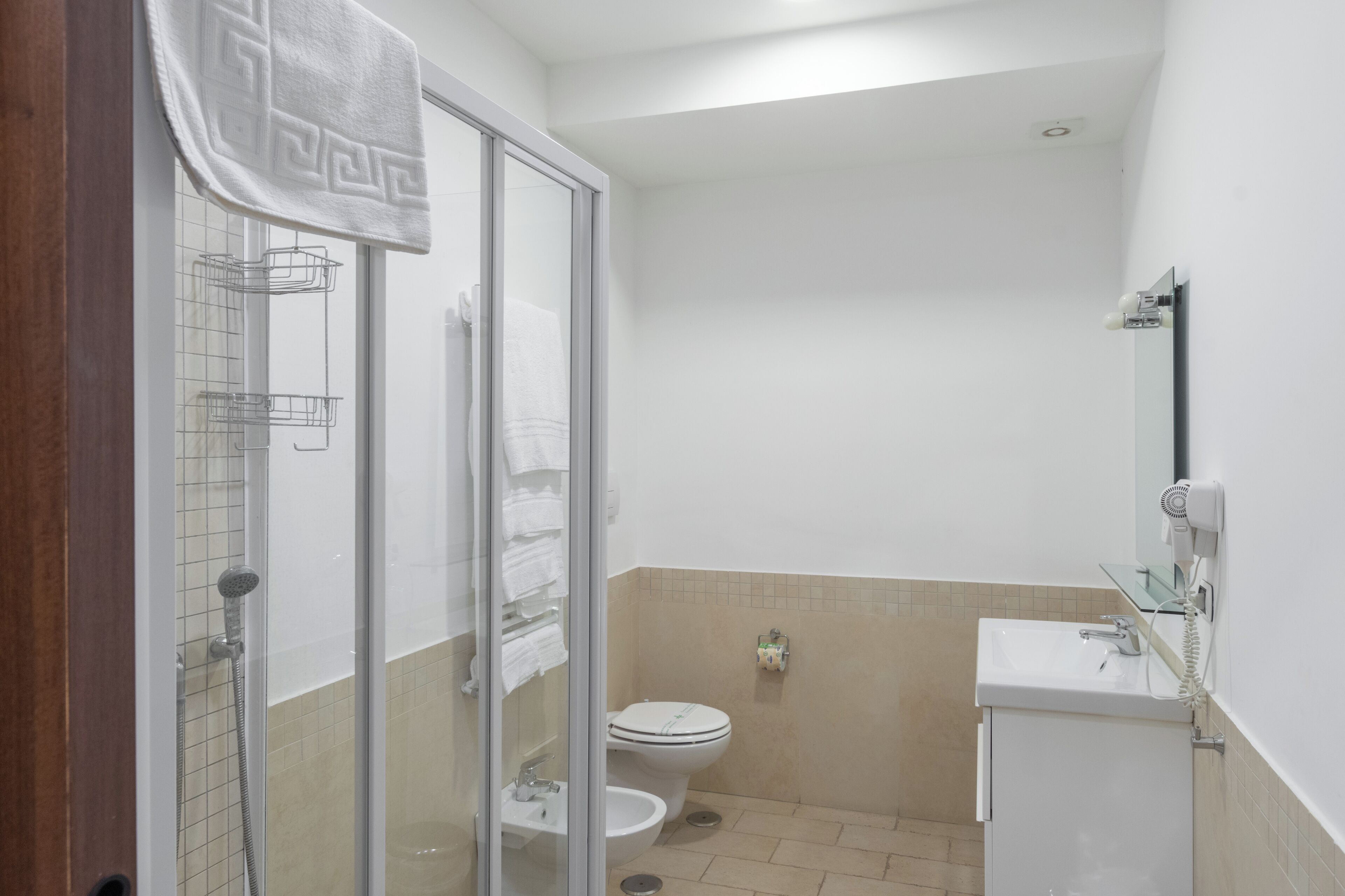 Une salle de bain avec une douche à parois de verre, des toilettes, un lavabo et un porte-serviettes.