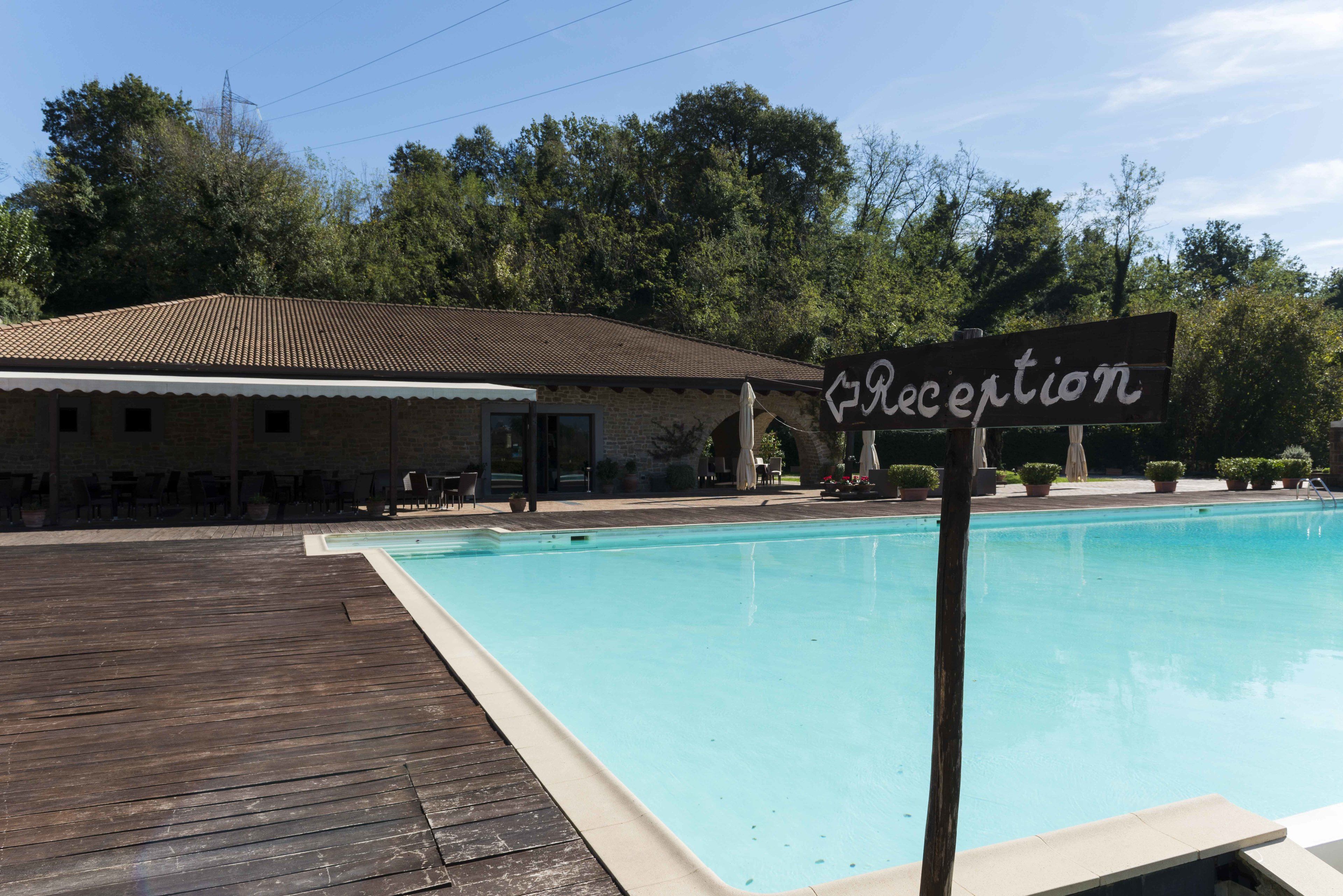 Un'area reception con un cartello, una piscina e un edificio con tetto in tegole.