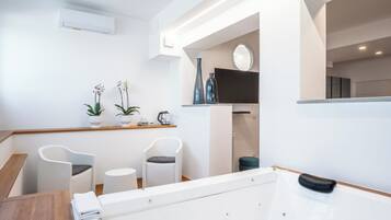 Un baño moderno con una bañera, dos sillones, una mesita y plantas decorativas.