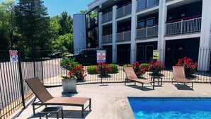 A poolside area with lounge chairs, a swimming pool, and a building with balconies in the background.
