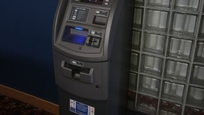 An ATM machine with a digital display, card slot, and cash dispenser.