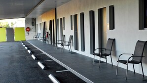 A covered outdoor seating area with rows of chairs and a fire extinguisher. - Copper City Motel (Pioneer)