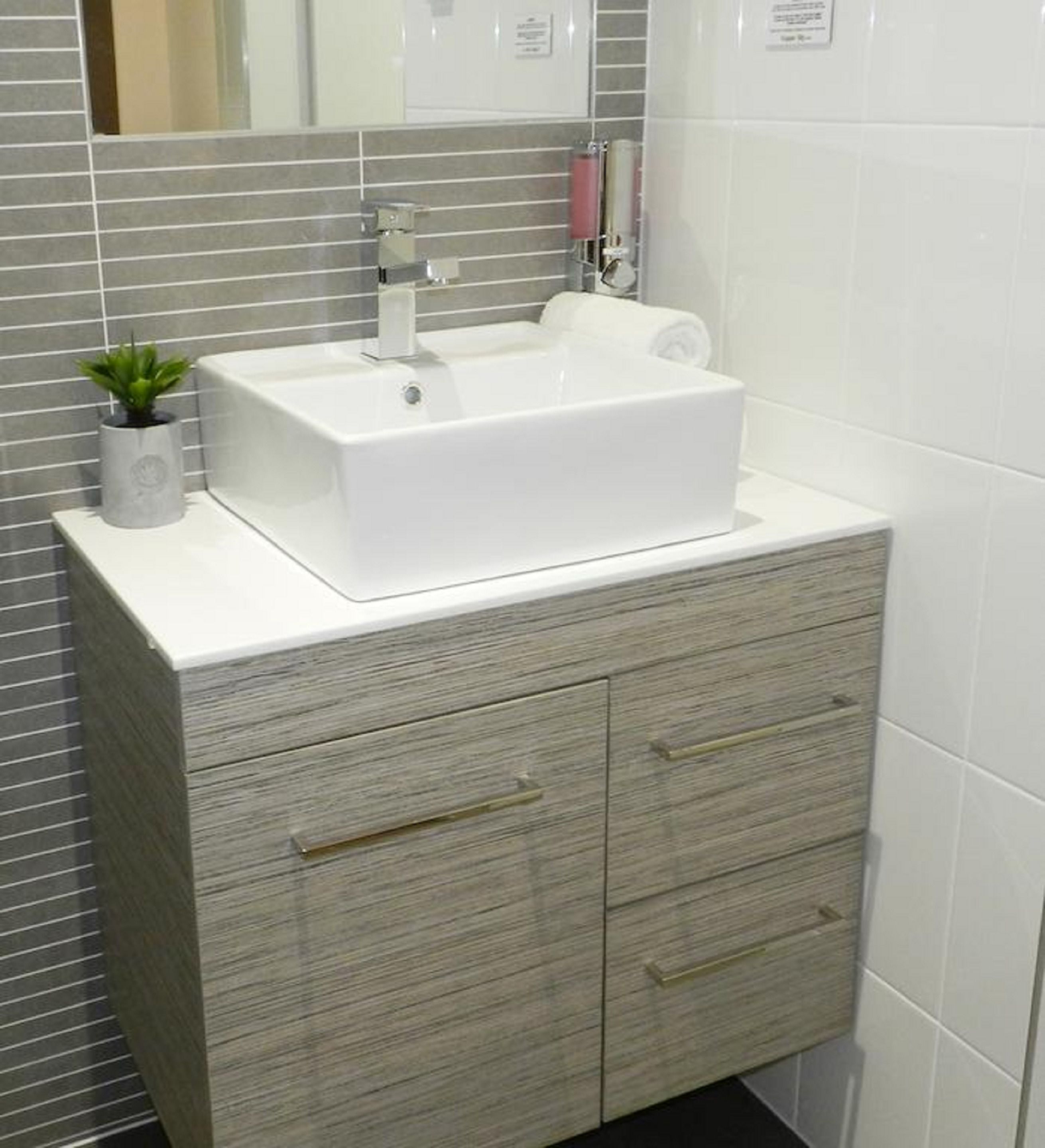 A bathroom with a white sink, a mirror, and a wooden vanity with drawers.