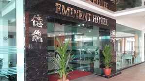 The exterior of the Eminent Hotel with a marble facade, glass entrance, and potted plants. - Eminent Hotel (Kota Kinabalu)