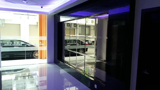 A modern hotel lobby with a glass partition, a car parked outside, and a clean, reflective floor. - Eminent Hotel (Kota Kinabalu)