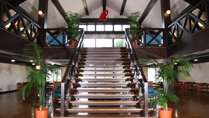 A spacious interior with a central staircase, wooden railings, and potted plants. - Grampus Resort Shirahama (Shirahama)