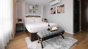 Ein ordentlich eingerichtetes Schlafzimmer mit einem großen Bett, Nachttischen, einer Bank mit Blumen und Wandbildern.