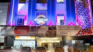 A hotel with a prominent 'CORDELA HOTEL' sign, a parking area, and a decorative facade with a patterned design. - Cordela Hotel Medan (Medan)