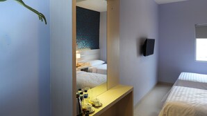A hotel room with a bed, a bedside table with toiletries, a mirror, and a TV mounted on the wall. - Cordela Hotel Medan (Medan)