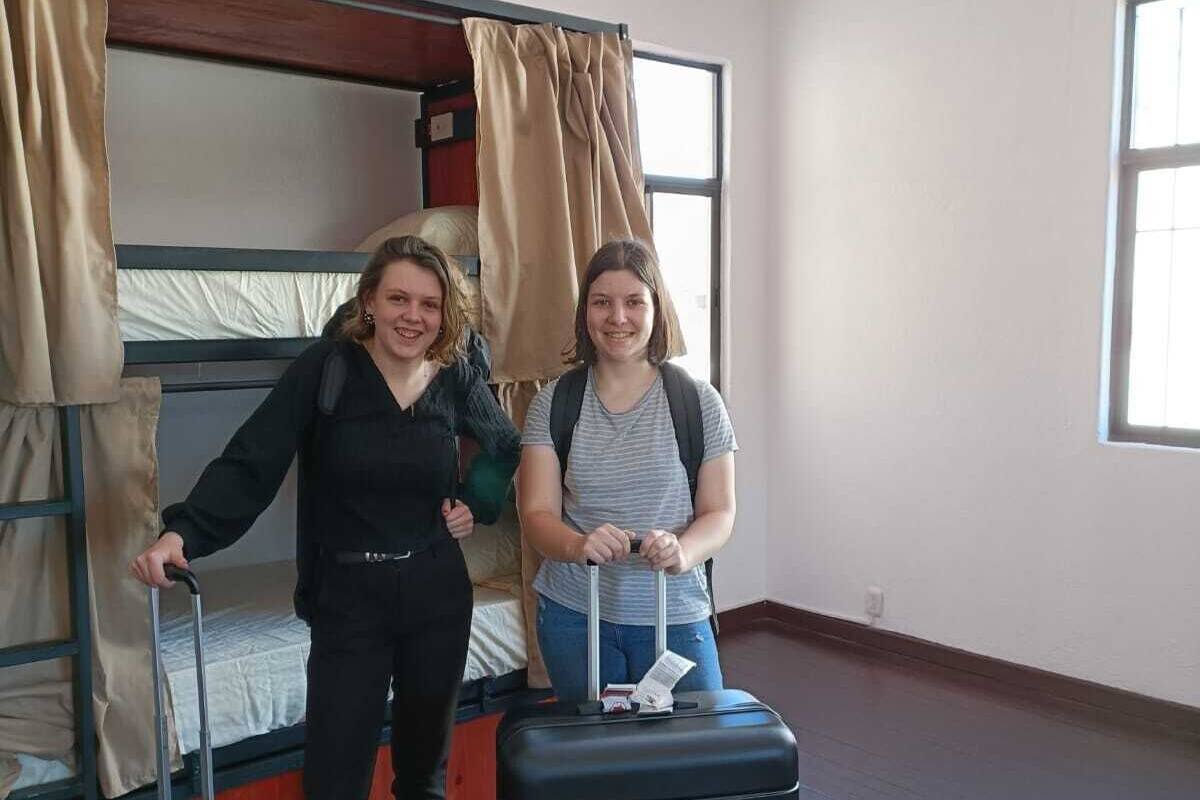 Une chambre avec des lits superposés, une fenêtre et une valise.