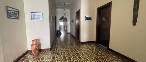 Un pasillo con suelo estampado, cuadros en las paredes y una puerta a la derecha.
