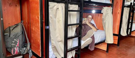Una habitación tipo dormitorio con literas, un armario de madera y una mochila en el suelo.