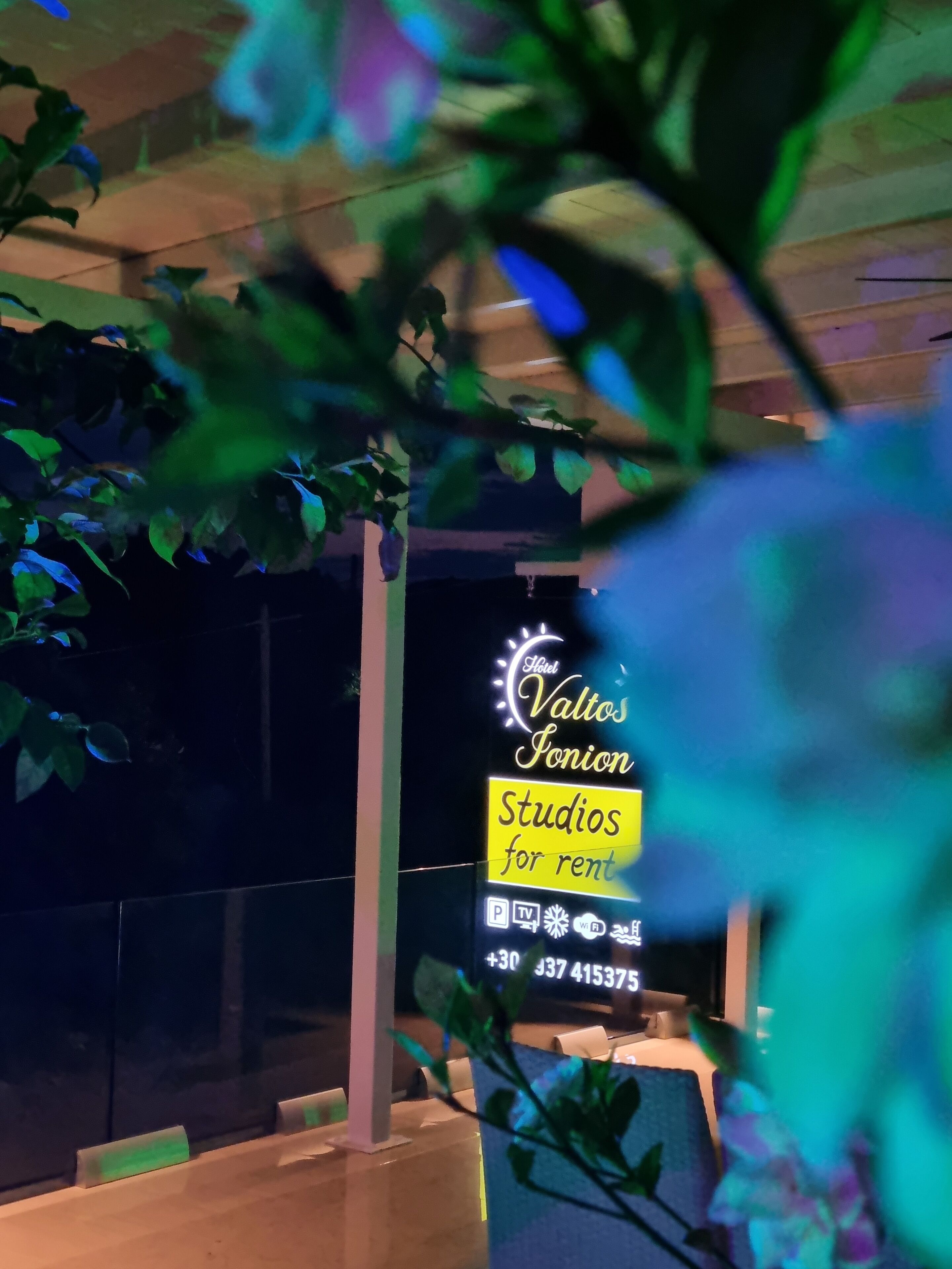 A hotel sign with the name 'Hotel Valtos Pionon' and 'Studios for rent' along with amenities like parking, TV, WiFi, and a contact number.
