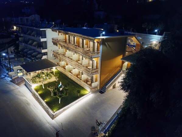 A multi-story hotel with balconies, outdoor seating, and a well-lit courtyard. - Valtos Ionion (Parga)