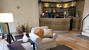Un vestíbulo de hotel con una recepción, un sofá, una mesa de centro y una lámpara.