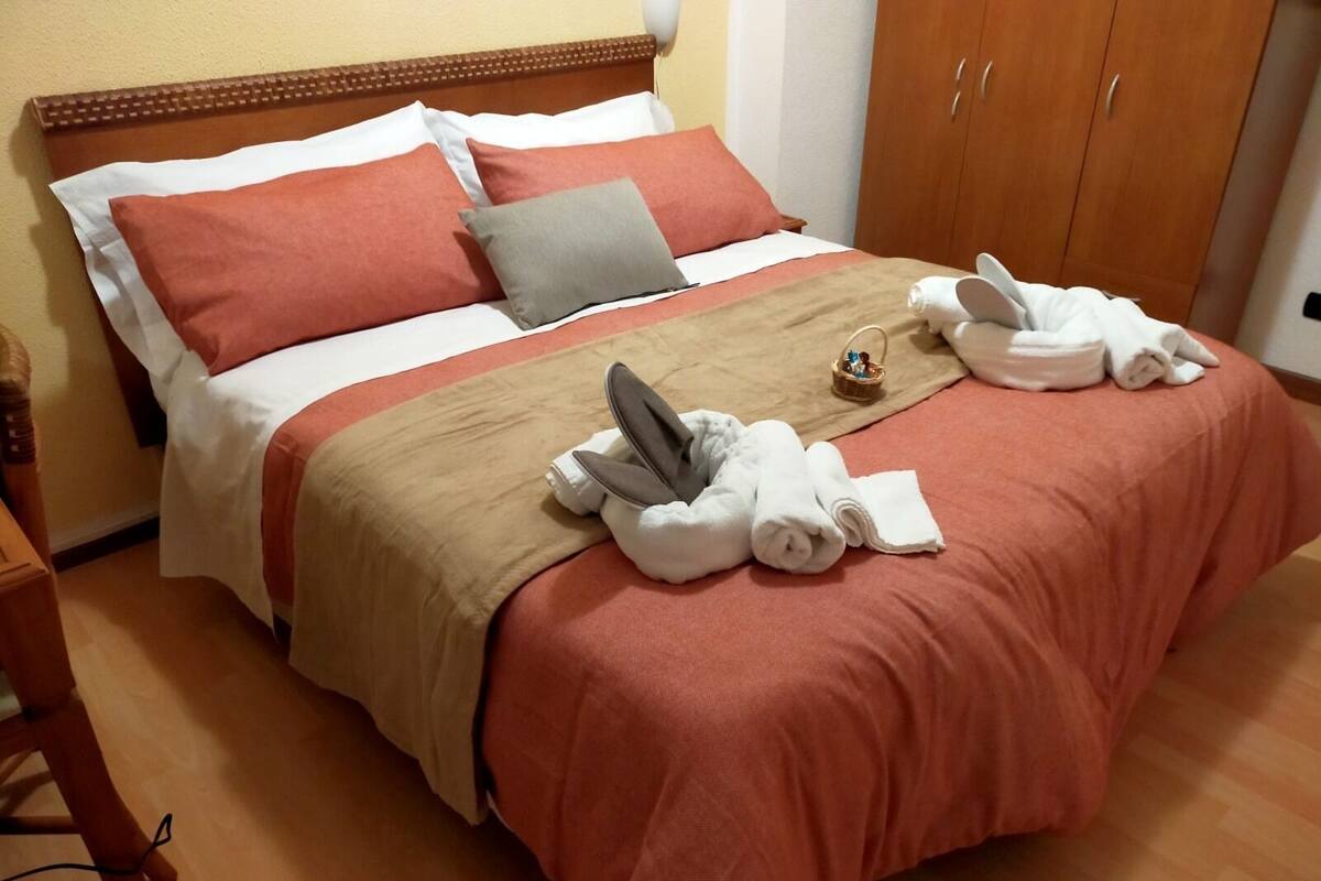 A neatly made bed with a brown and white bedspread, two pillows, and a small basket on the bed.