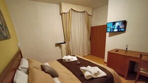Una habitación de hotel con cama, escritorio, televisión y armario.