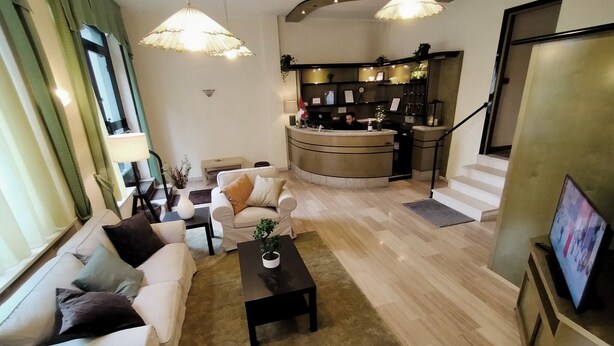 Una sala moderna con un conjunto de sofá, una mesa de centro y un televisor. Hay una zona de cocina con mostrador y una escalera que lleva a otro nivel.