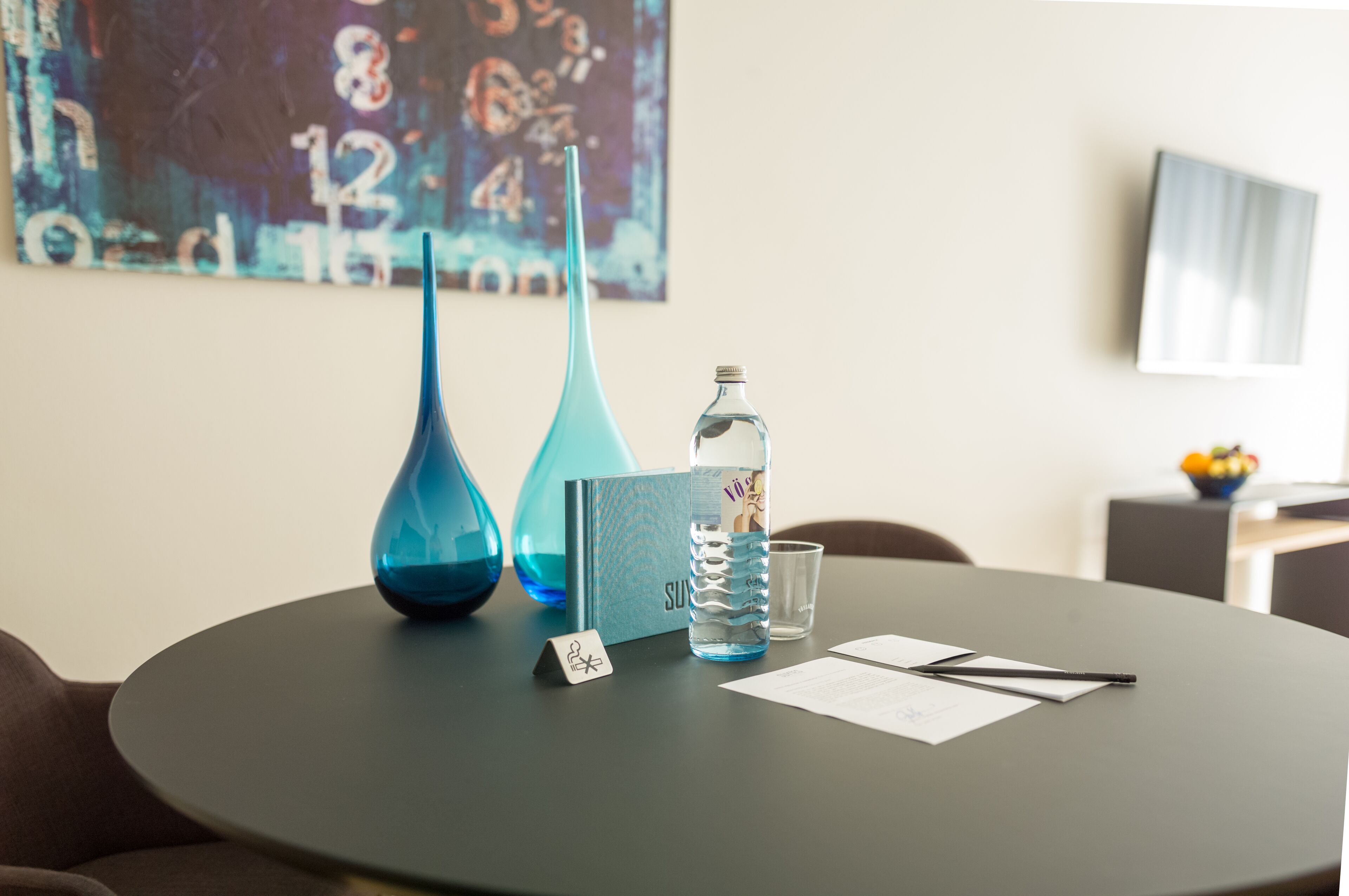 A round table with a water bottle, two vases, a menu, and a small sign.