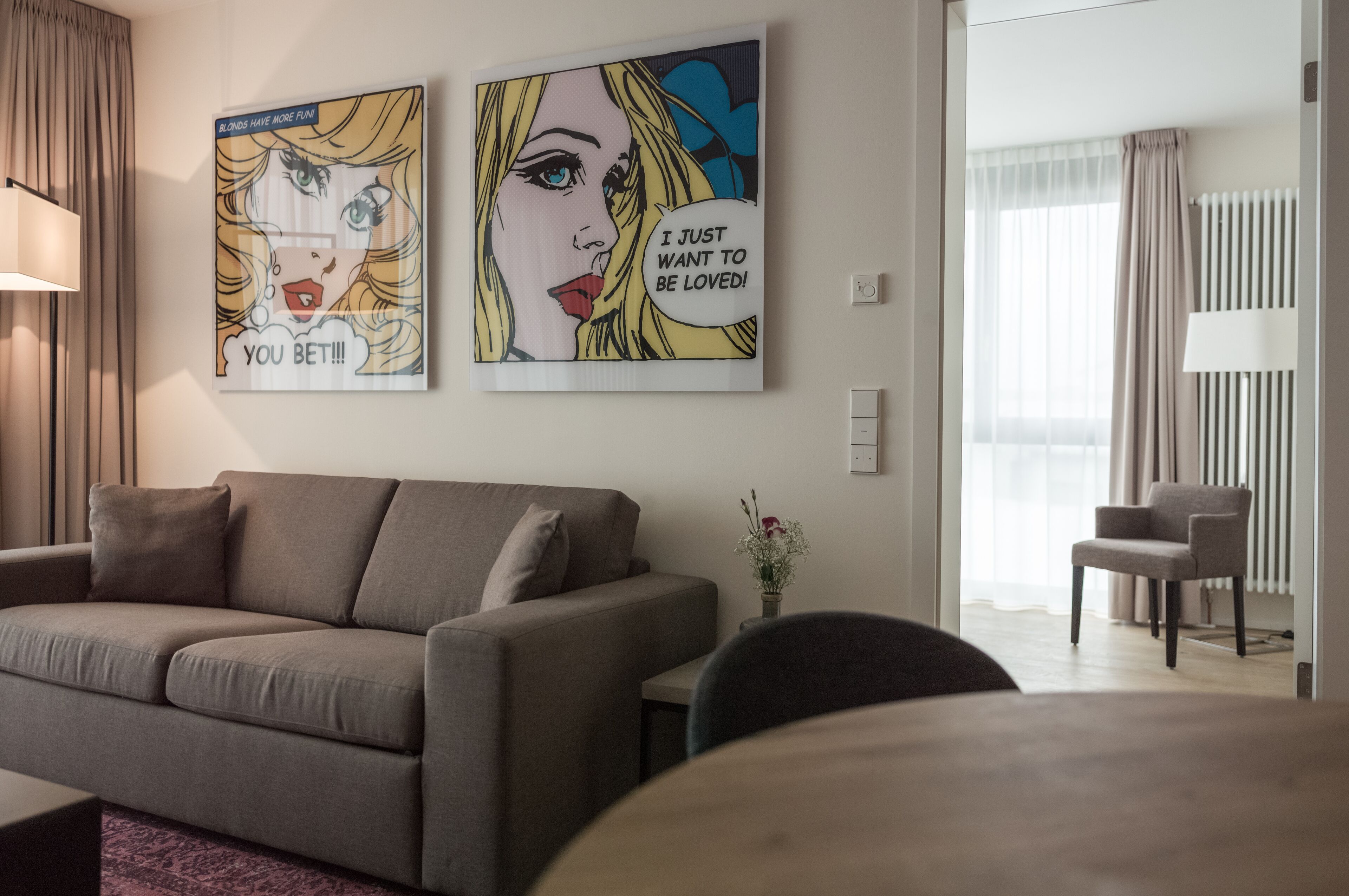 Een woonkamer met een bank, een bijzettafeltje en twee kunstwerken in lijsten aan de muur.