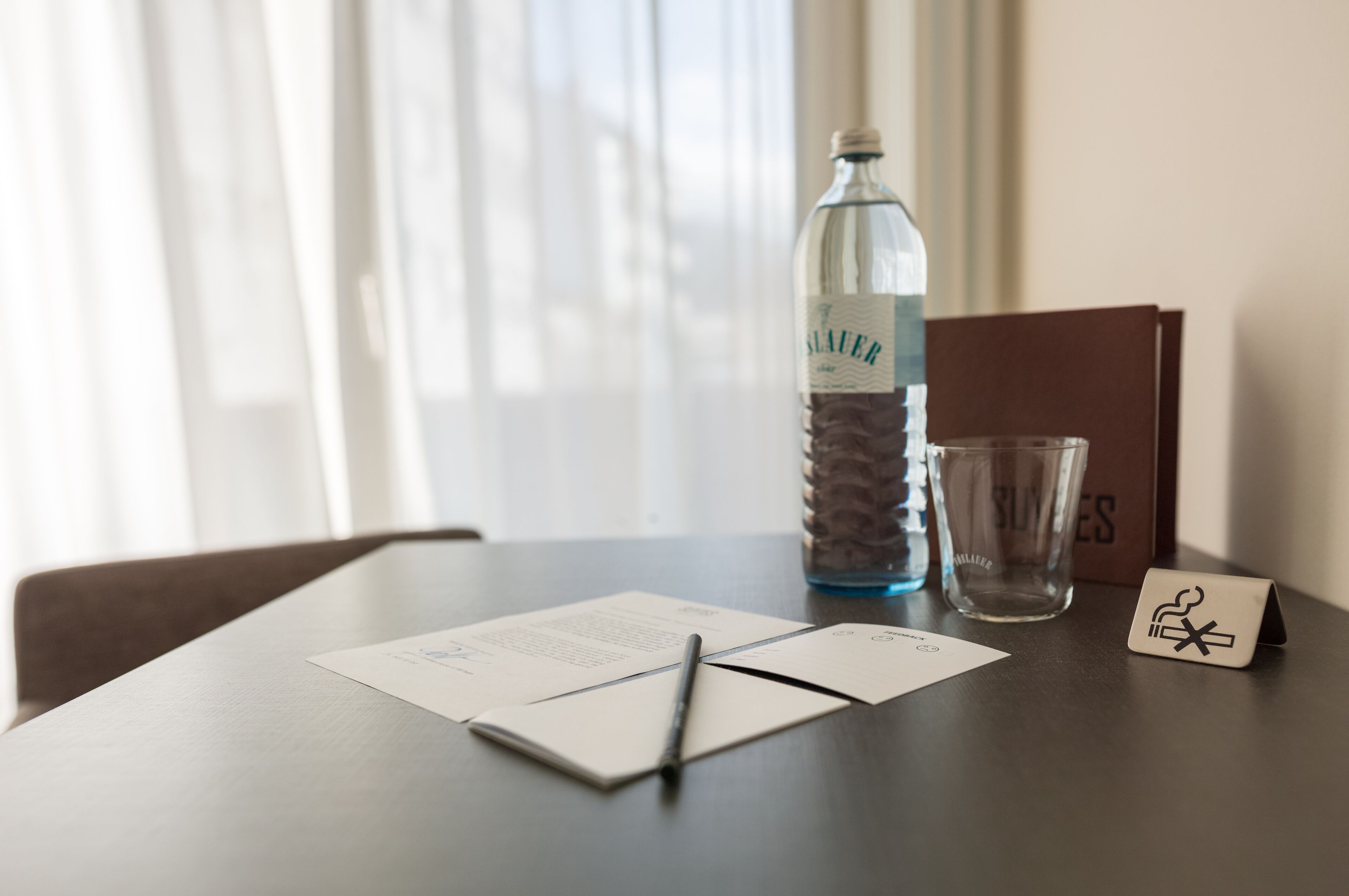 A table with documents, a pen, a bottle, and a glass.