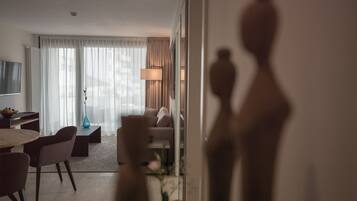 A modern hotel room with a dining area, a sofa, a lamp, and a view of the outdoors.