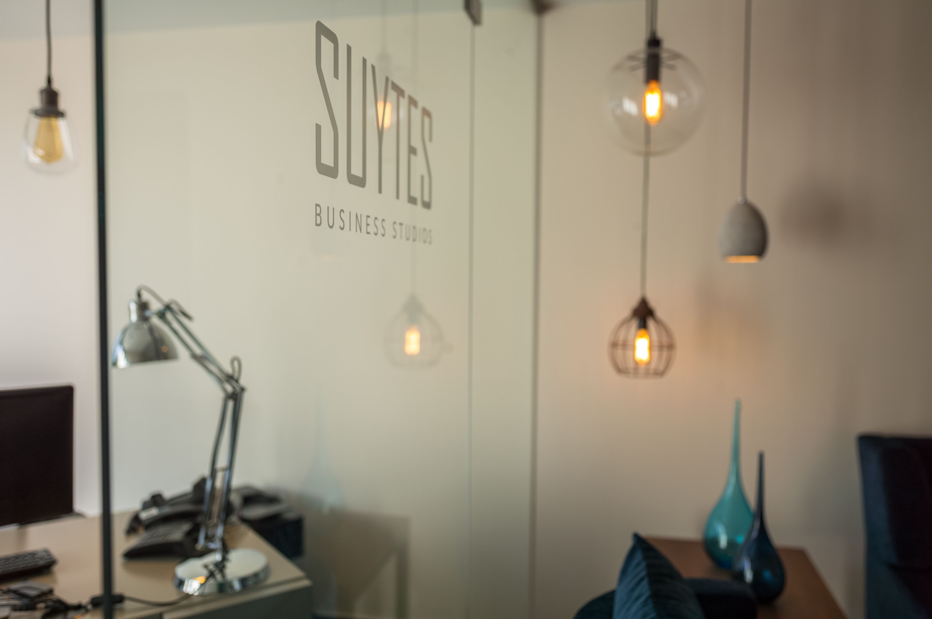 Ein moderner Arbeitsraum mit Schreibtisch, Lampe und dekorativen Vasen.