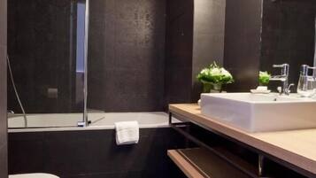 Un baño moderno con inodoro blanco, bañera y un espejo grande.