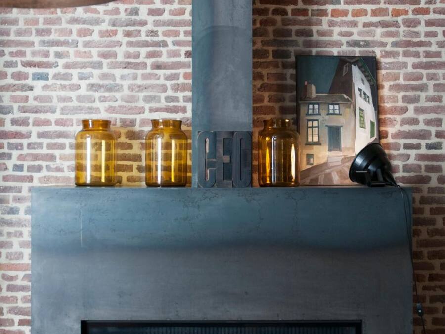 A modern fireplace with a metal frame, a brick wall, and a black lamp.