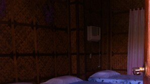 Una habitación con dos camas, piso de madera y aire acondicionado de pared.
