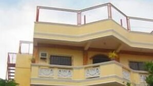 Un edificio de varios pisos con balcones, entrada a nivel de calle y un cartel.
