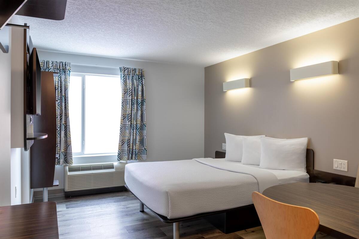 Une chambre d’hôtel moderne équipée d’un lit, de tables de chevet, d’un bureau et d’une chaise.