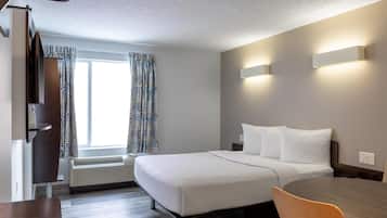 A modern hotel room with a bed, bedside tables, a desk, and a chair.