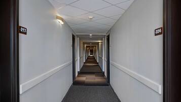A long, narrow hallway with carpeted floors and white walls, featuring door numbers 217 and 224.