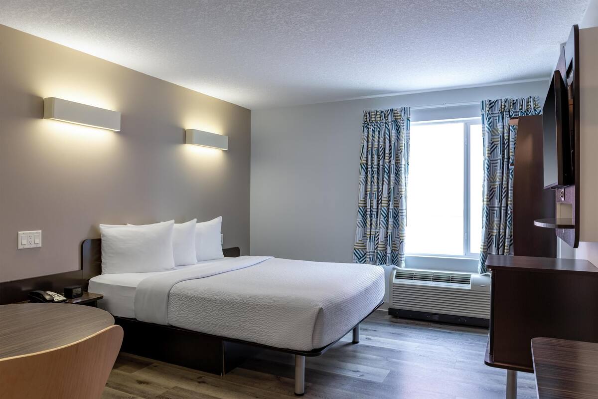 Une chambre d’hôtel moderne, dotée d’un grand lit, de tables de chevet, d’un bureau et d’une chaise.