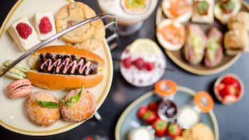 Una variedad de postres y pasteles en una mesa, como galletas, macarons y un pastel cubierto de chocolate.