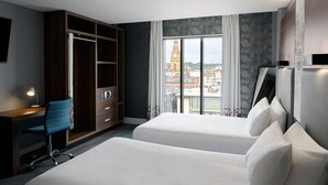 A hotel room with two beds, a desk, a wardrobe, and a large window with a city view. - Aloft by Marriott Liverpool (Liverpool)