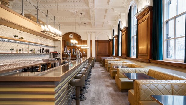 A bar area with a long counter, multiple stools, and seating with tables. - Aloft by Marriott Liverpool (Liverpool)