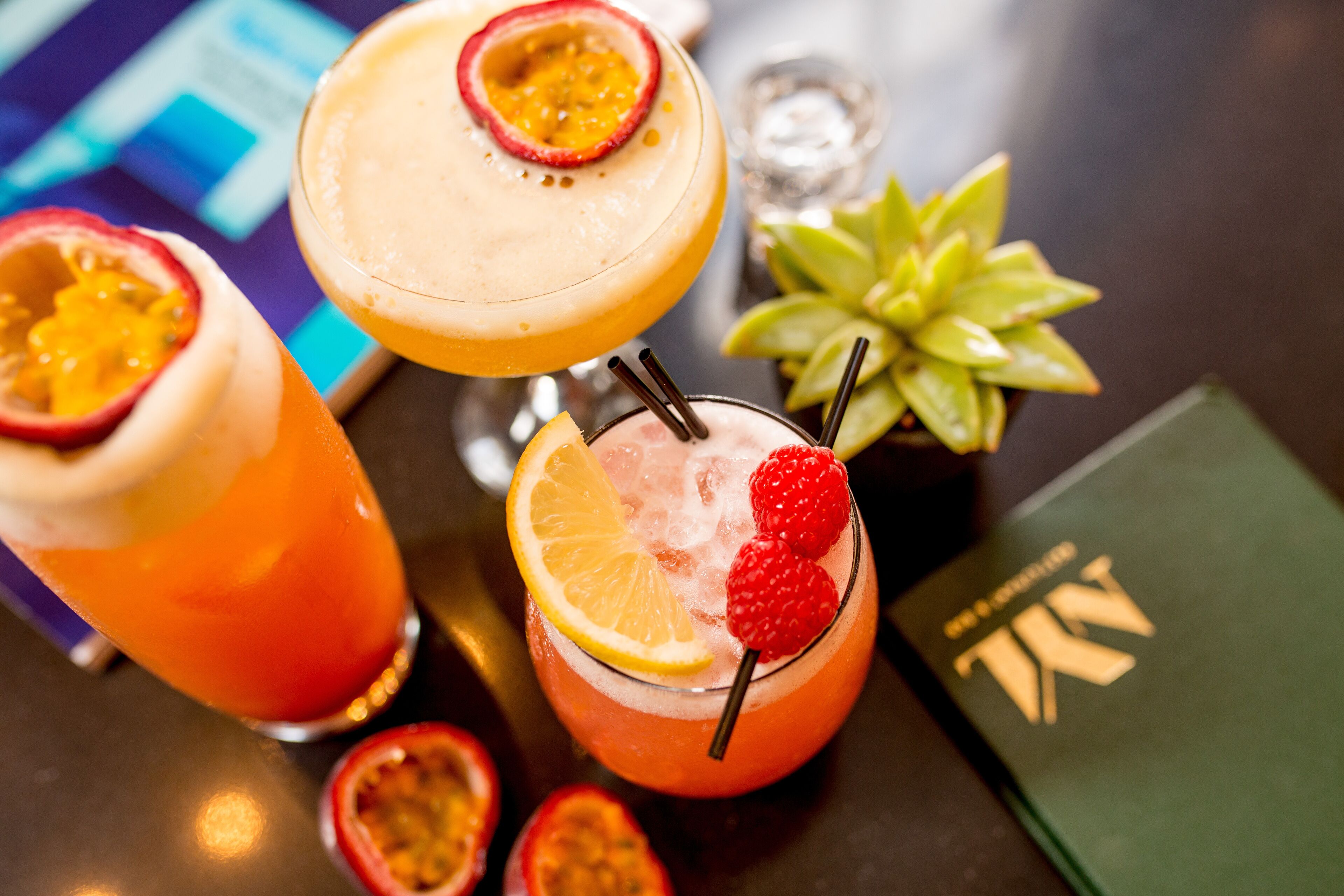 Tre cocktail con guarnizioni di frutta su un tavolo.