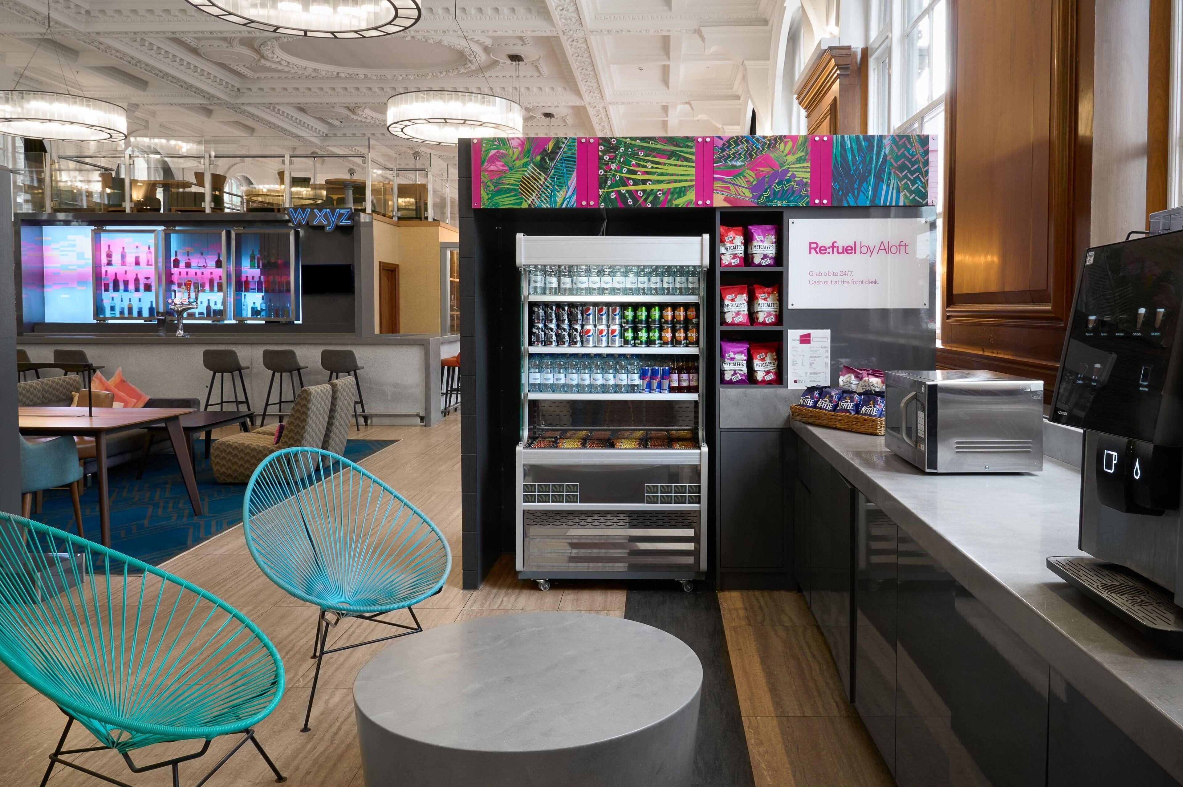 Un espace bar moderne avec un distributeur automatique aux couleurs vives, des sièges et un appareil à café.