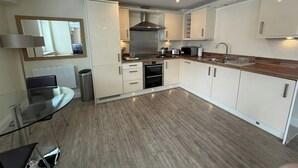 Una cocina moderna con armarios blancos, electrodomésticos de acero inoxidable y encimera de madera.