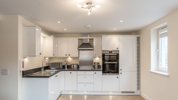 Una cocina moderna con armarios blancos, electrodomésticos de acero inoxidable y una isla central con pileta.