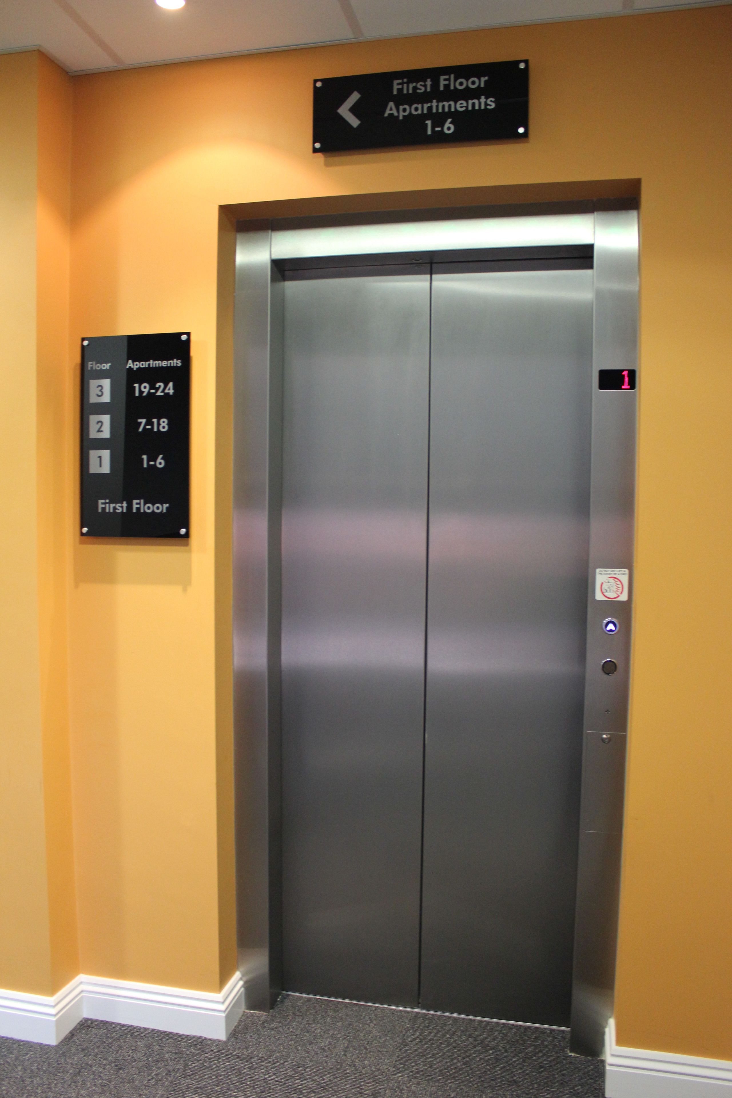 An elevator with a sign indicating first-floor apartments 1-6.