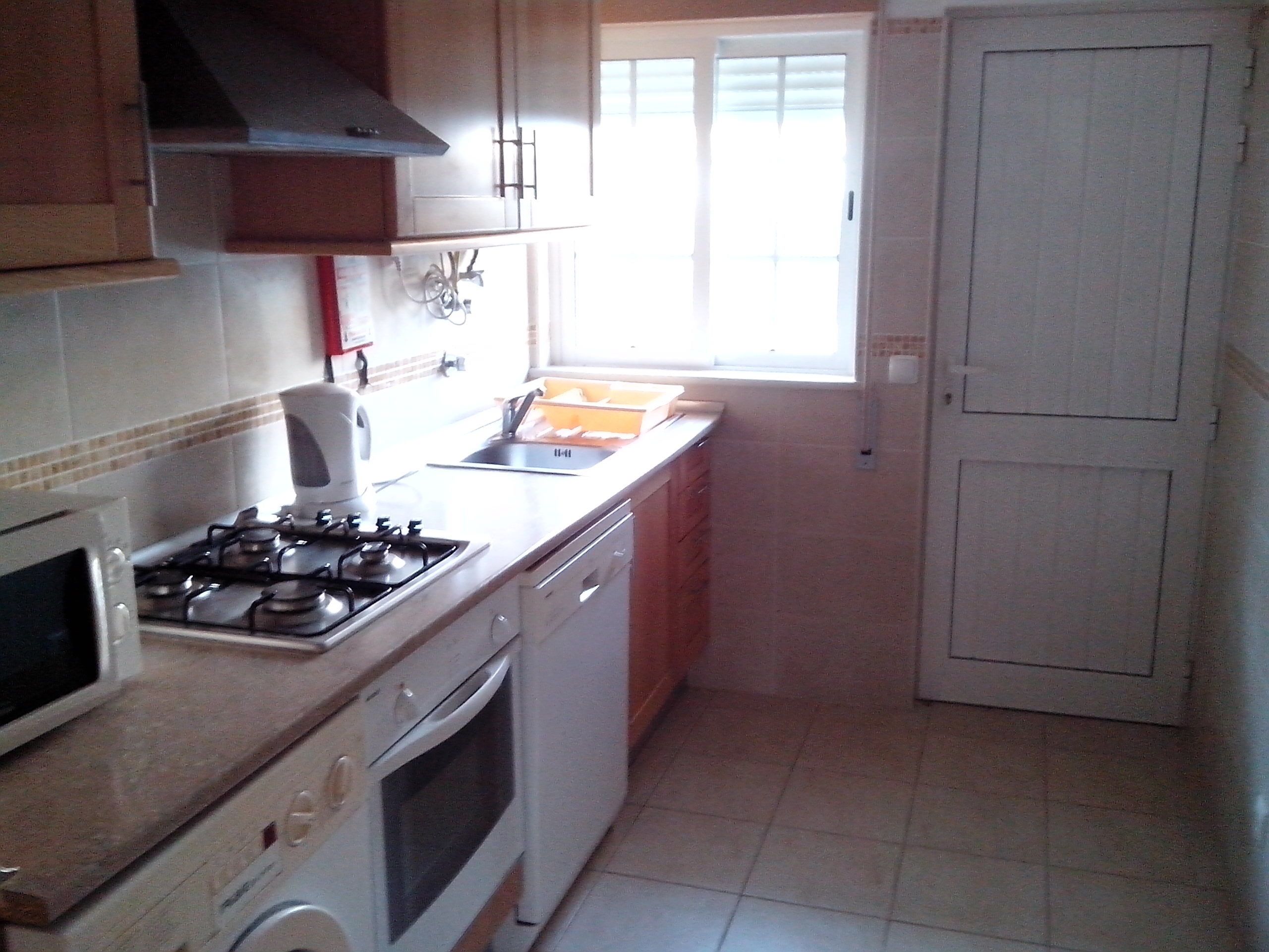 A kitchen with a stove, oven, microwave, and a window with blinds.