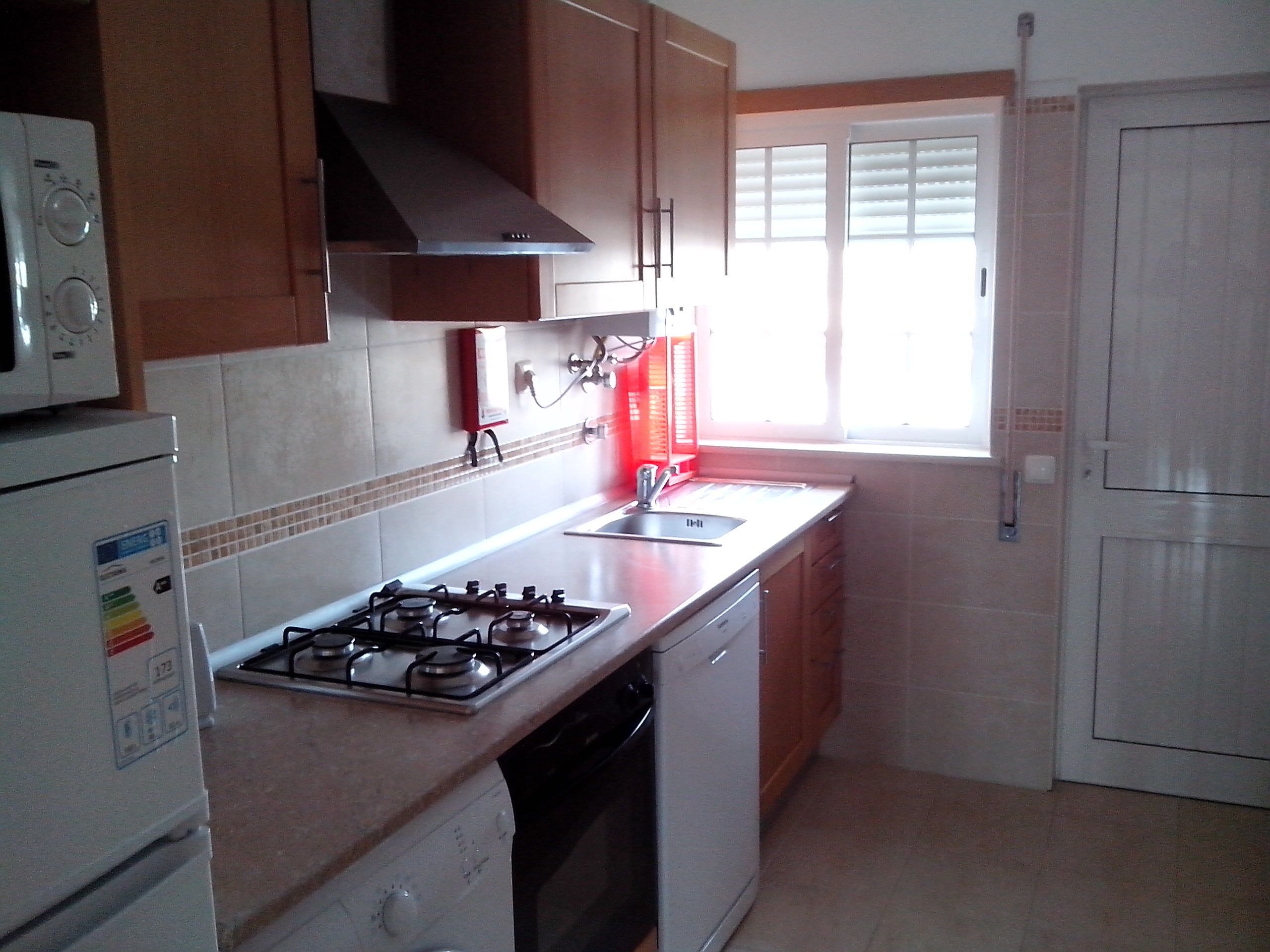 A kitchen with a gas stove, a microwave, a sink, and a refrigerator.