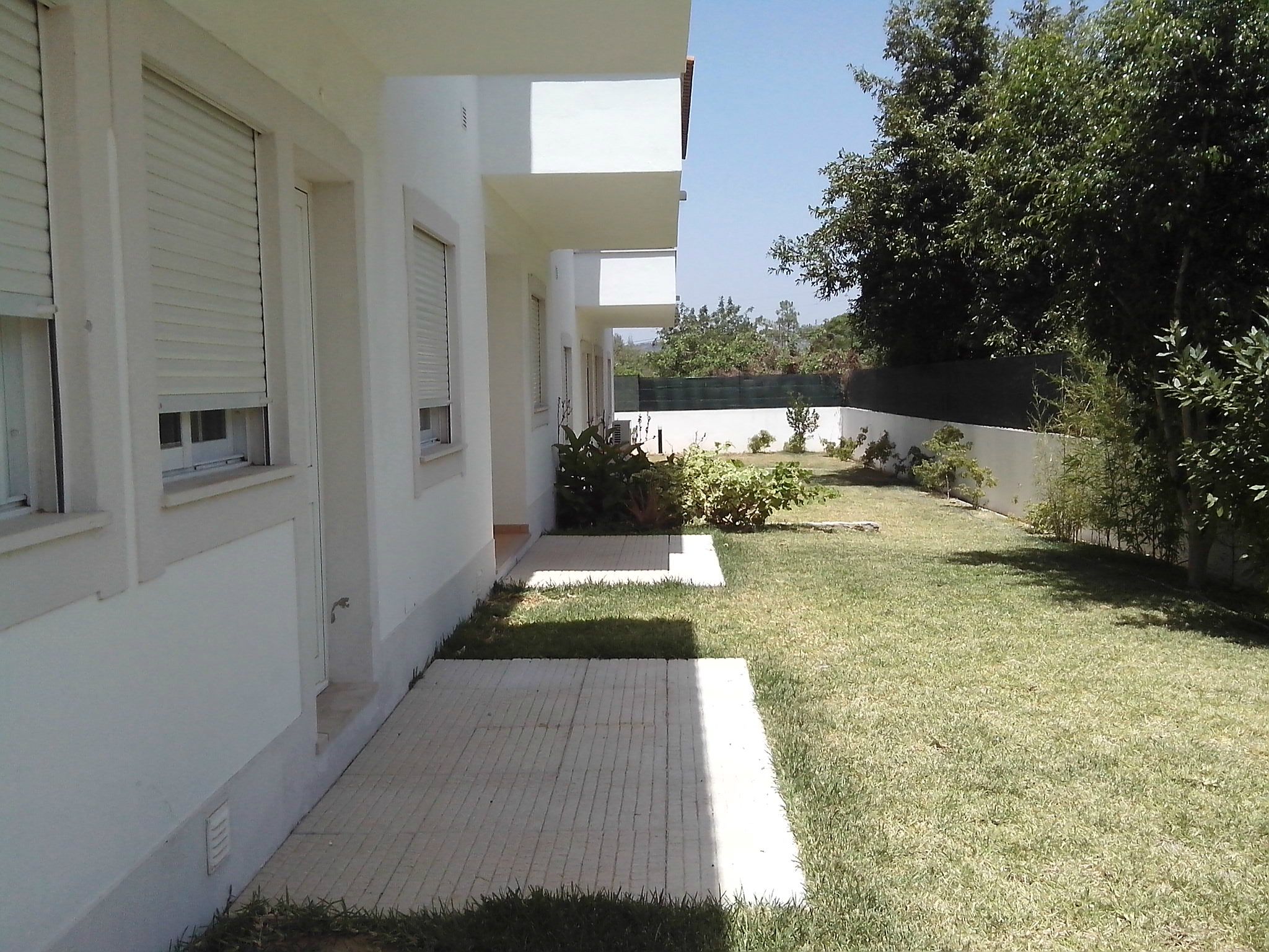 A white building with a paved walkway and a grassy area.